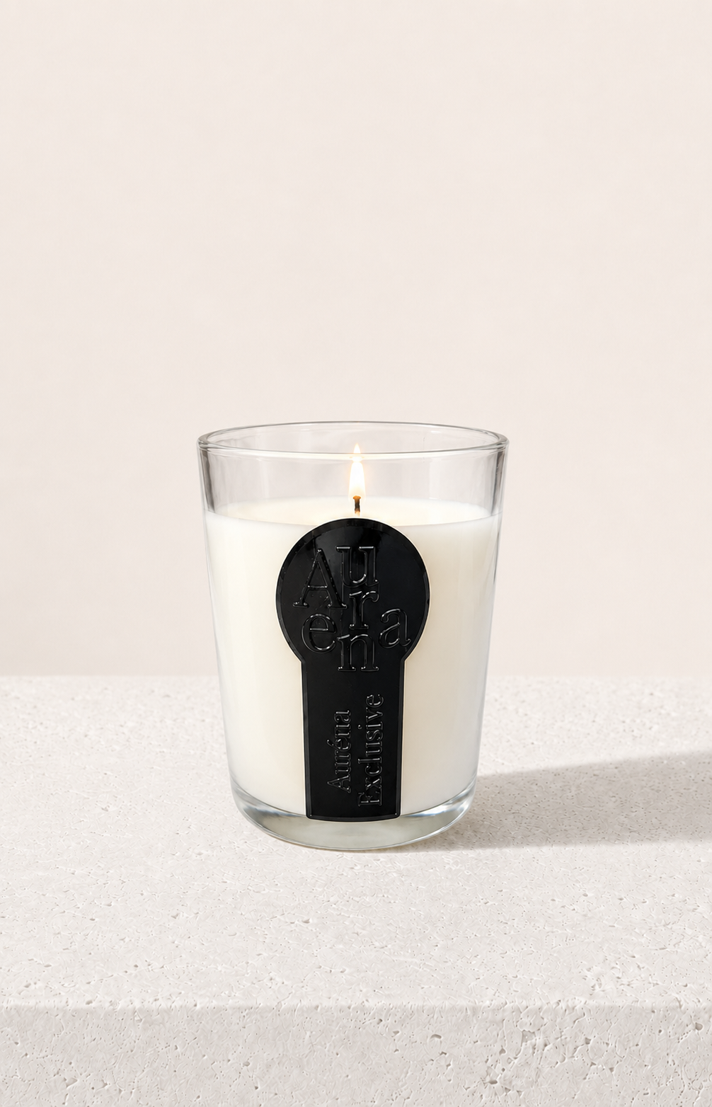 Minimalistische Auréna Duftkerze im Glas mit schwarzem 3D-Label auf reinweißem Hintergrund, elegante Luxus-Produktdarstellung.