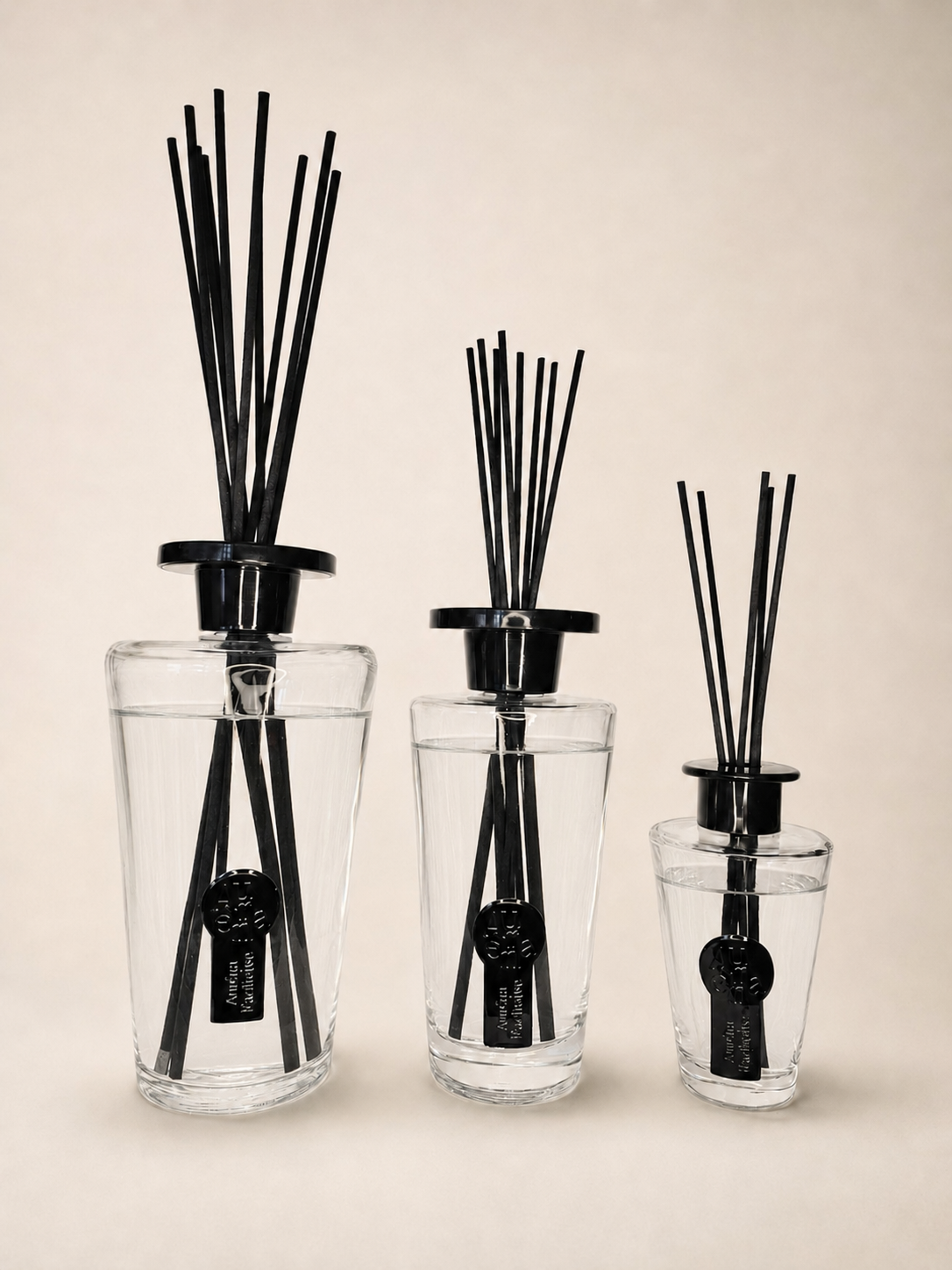 Auréna Diffuser-Kollektion in drei Größen, der große 1.000-ml-Diffuser links, mit klarer Duftflüssigkeit und schwarzen Stäbchen.

