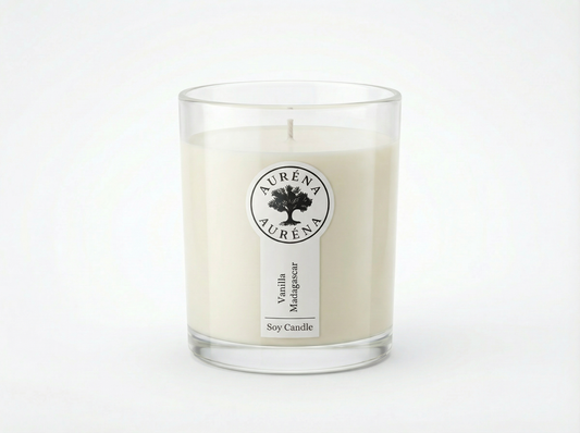 „Handgegossene Auréna Duftkerze im klaren Glas mit weißem Wachs, schlichtem Etikett und Logo, Duft Vanilla Madagascar, vor weißem Hintergrund.“