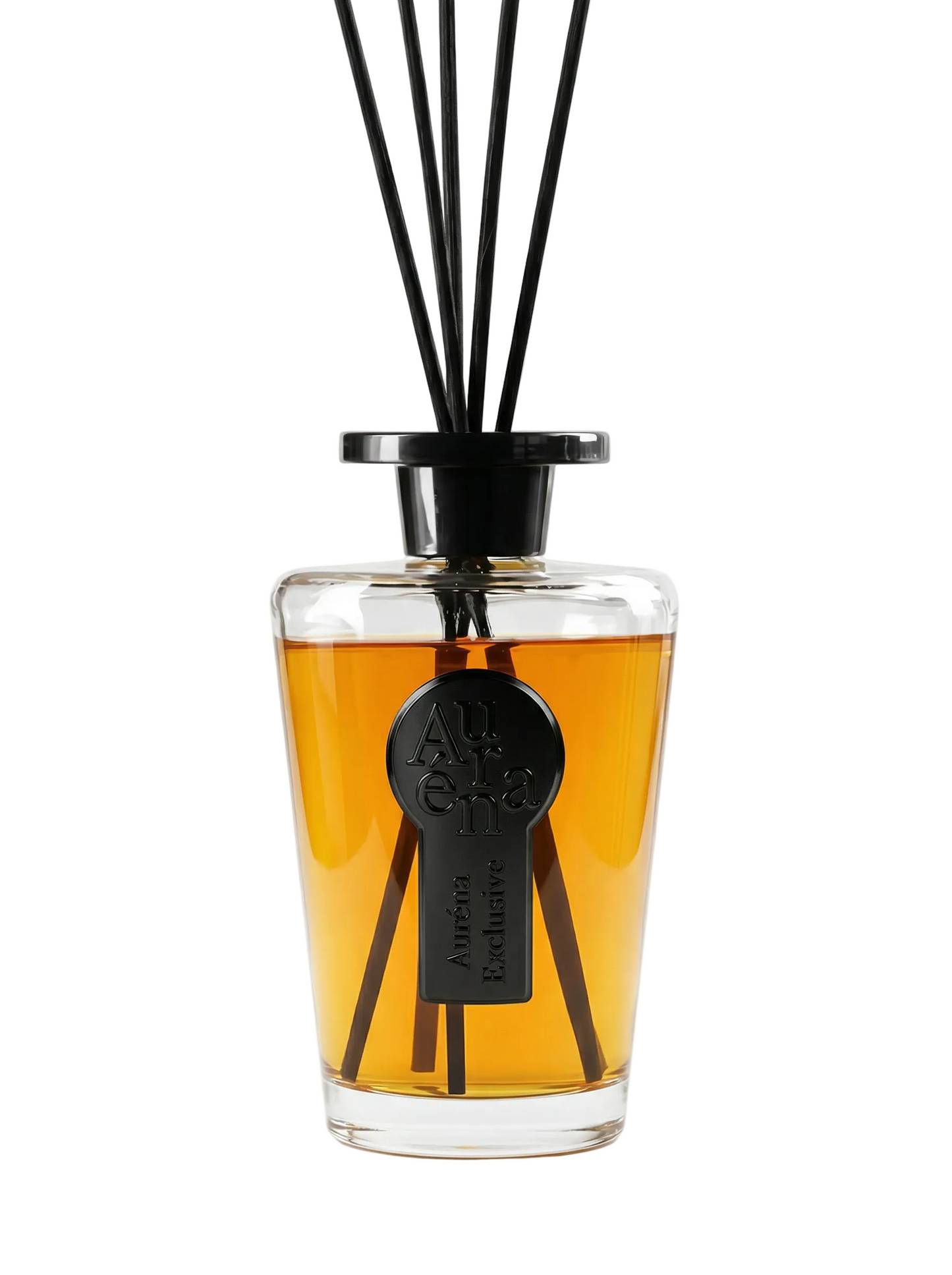 Luxuriöser Auréna Raumduft-Diffuser aus klarem Glas mit bernsteinfarbener Duftflüssigkeit, schwarzem Deckel und schwarzen Duftstäbchen. Auf der Vorderseite befindet sich ein schwarzes, geprägtes 3D-Label mit der Aufschrift „Auréna Exclusive“. Minimalistisches High-End Produktfoto vor reinweißem Hintergrund.
